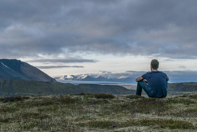 man sitting on top of mountain observing the world