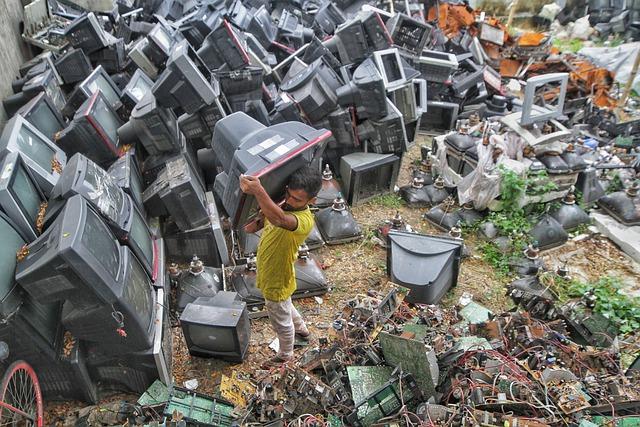 man carrying television from an e-waste landfill