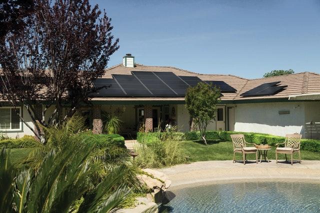 home with solar panel on roof top and green garden