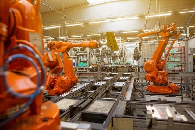 orange robotic arm in an assembly line