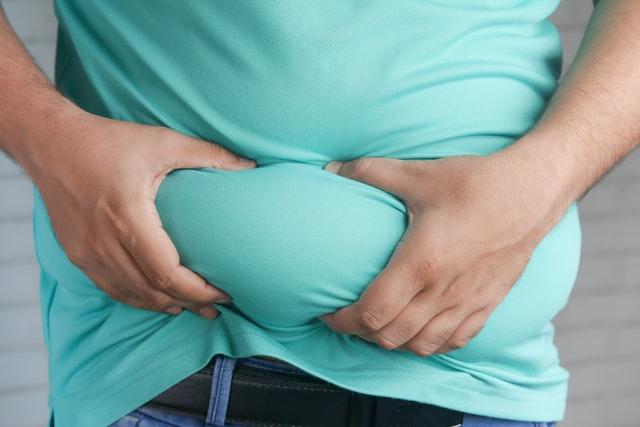 man in blue shirt holding his fat belly