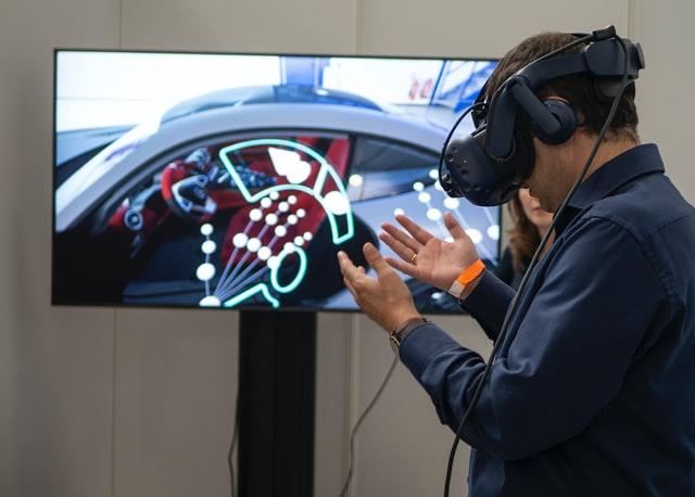 man with virtual reality headset and sensor interacting in front a screen