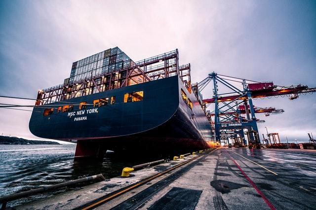 a blue shipping container being unloaded at port