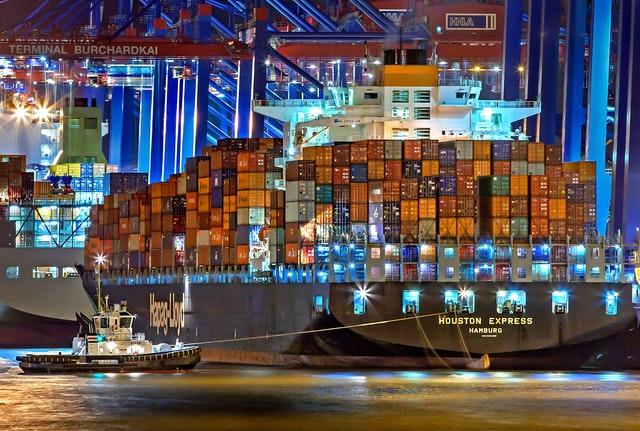 big shipping container being tug by a tugboat at night