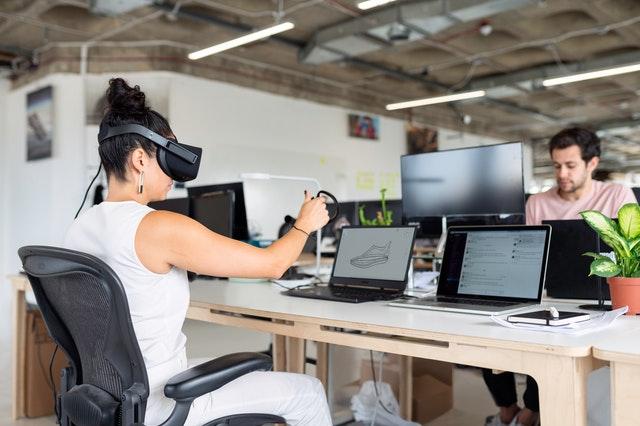 woman using laptop with vr headset in office