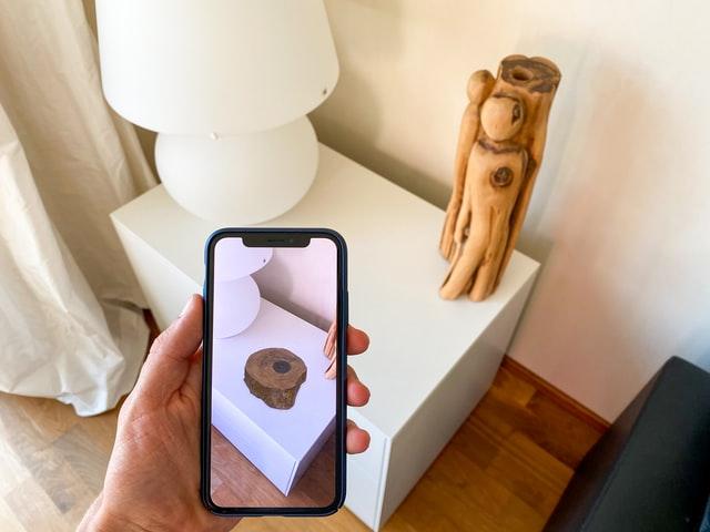 a man using iPhone to superimpose object in room through augmented reality