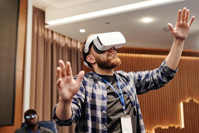 man wearing virtual reality headset raising his hands in the air