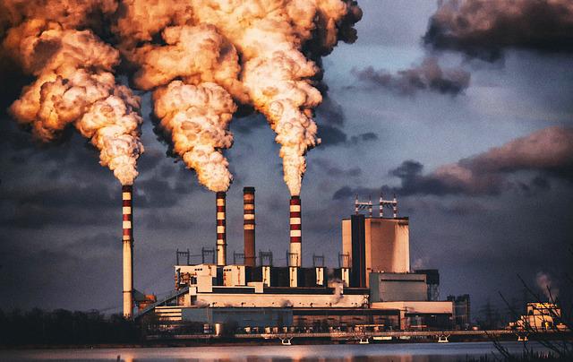 heavy dark smoke coming out of three chimney at a coal factory