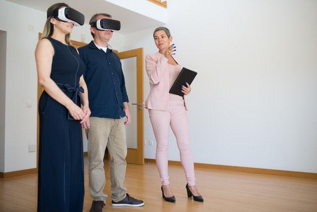 a couple using a virtual reality headset beside a realtor for virtual tour of apartment